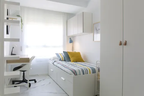 Habitación individual exterior con cama, escritorio y luz natural